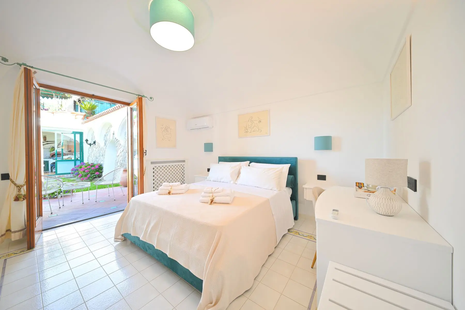 The Chiaro di luna room with the petrol-green headboard and the French door open onto the garden