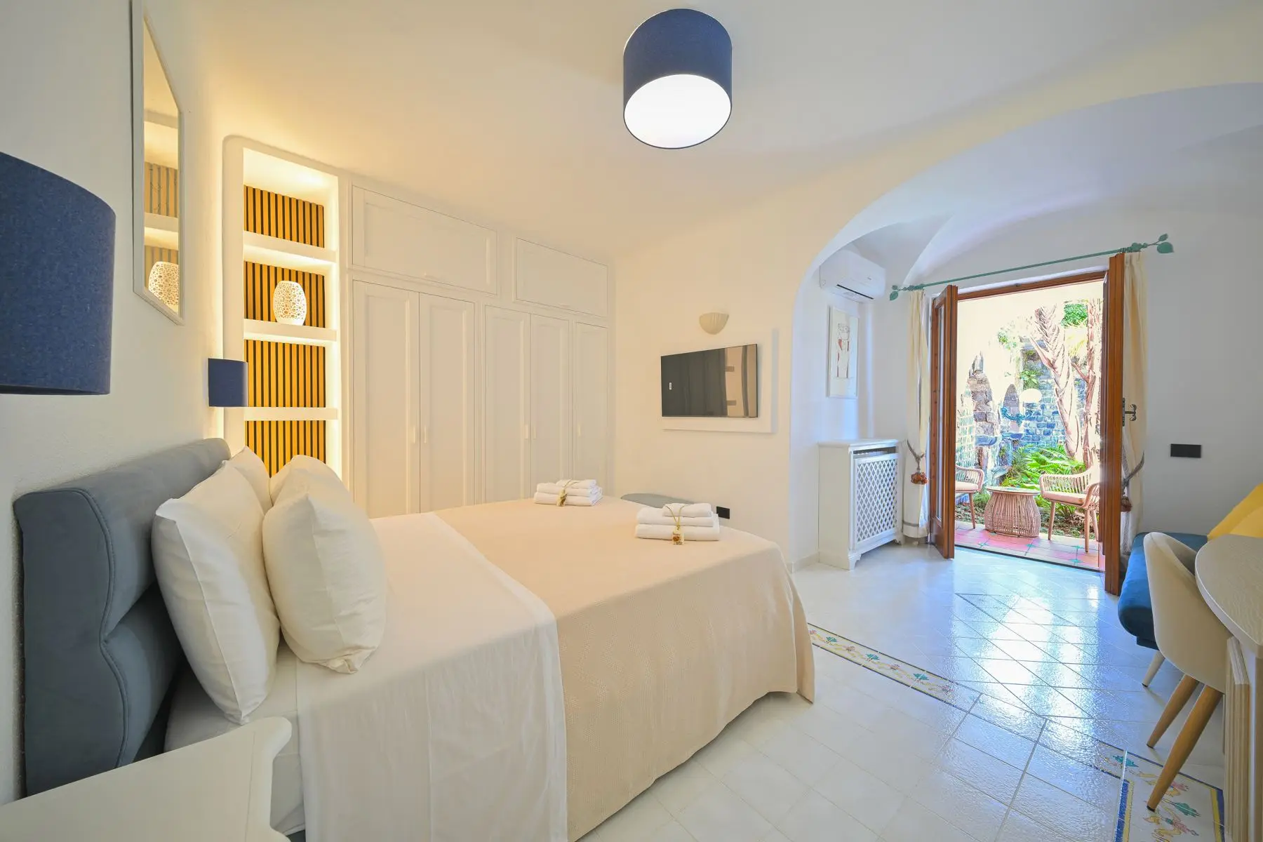 The room with the white vault and the door open onto the patio among the ferns