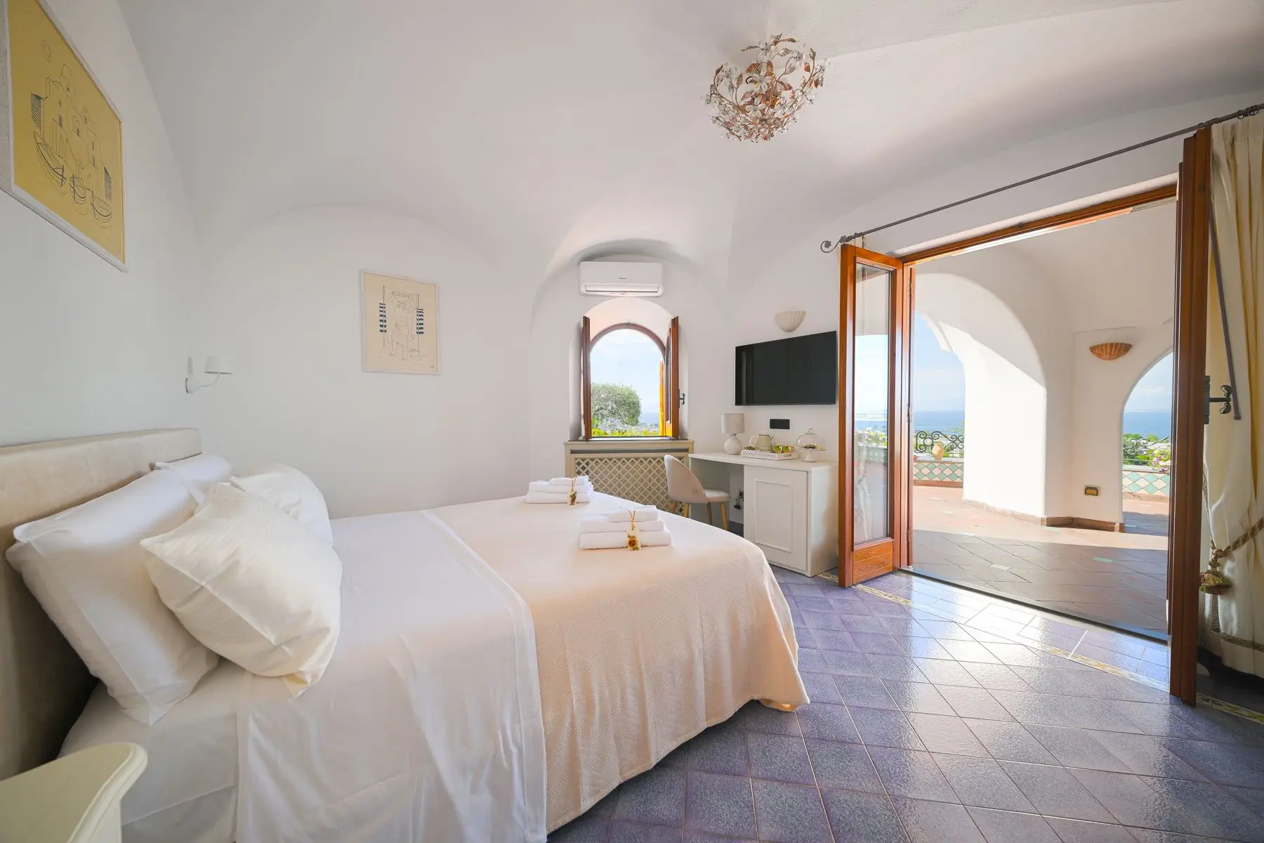 The Deluxe room with white vaults and French doors open onto the sea view terrace