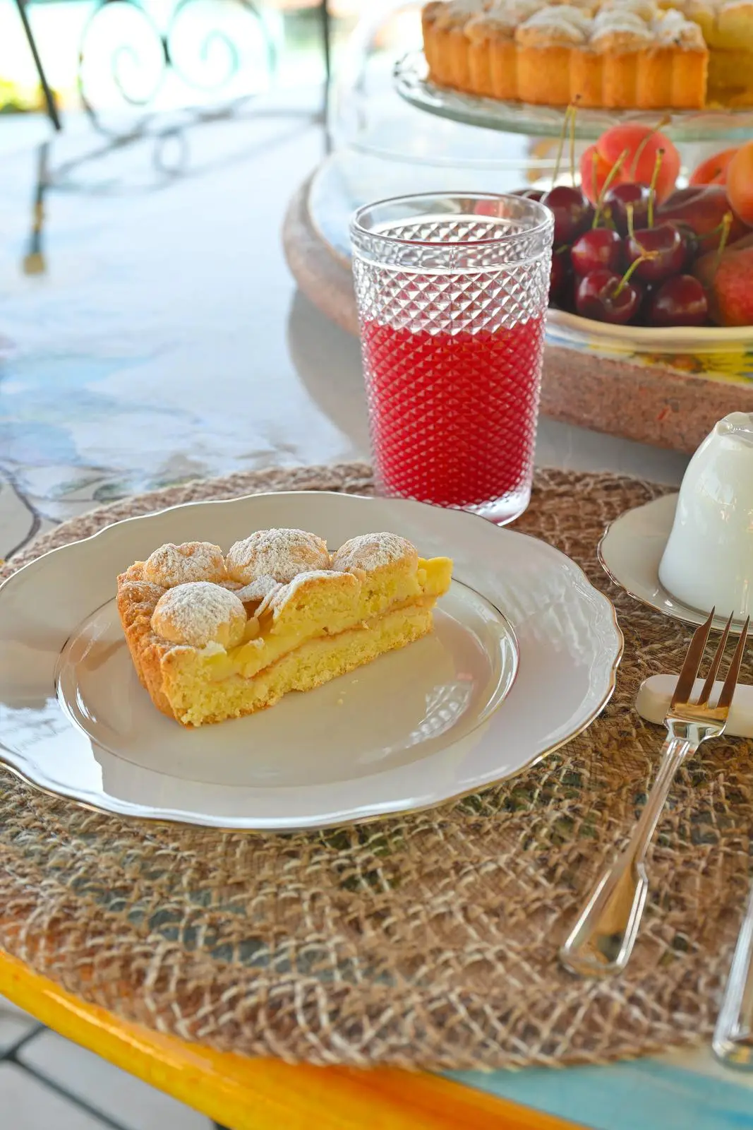 A slice of tart and a red juice on the laid table