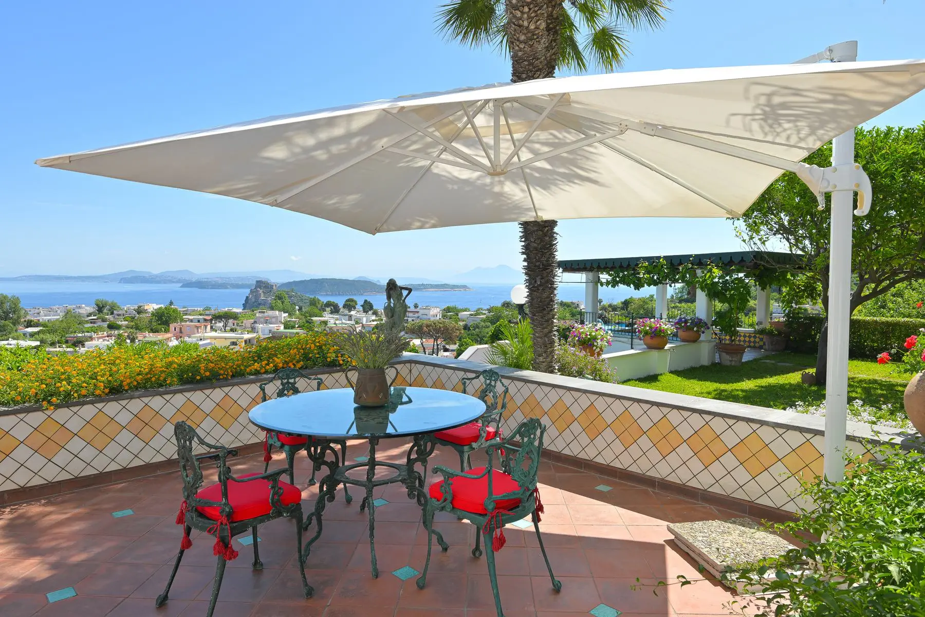 The majolica terrace with its parasol and table, facing the bay and the Aragonese Castle