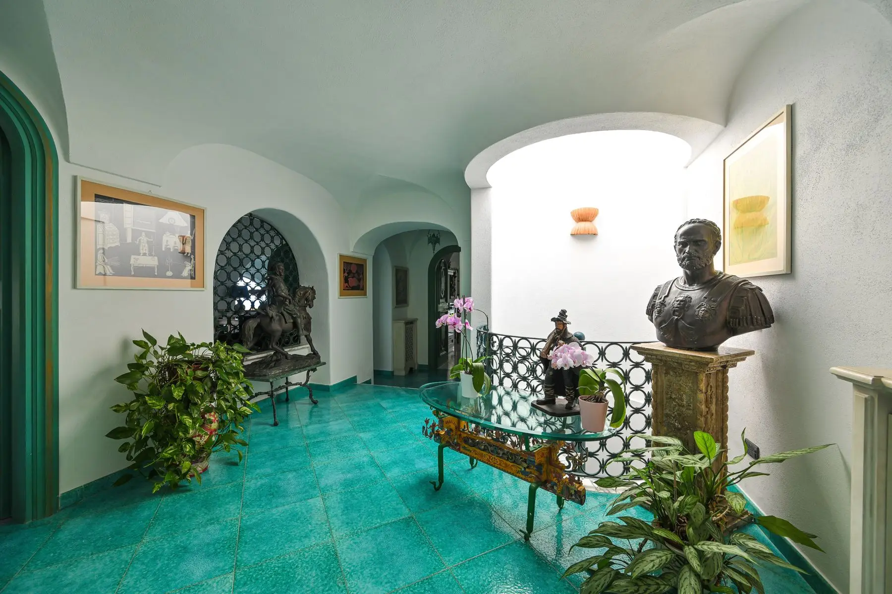 The entrance with bronze sculptures, plants and the green majolica floor
