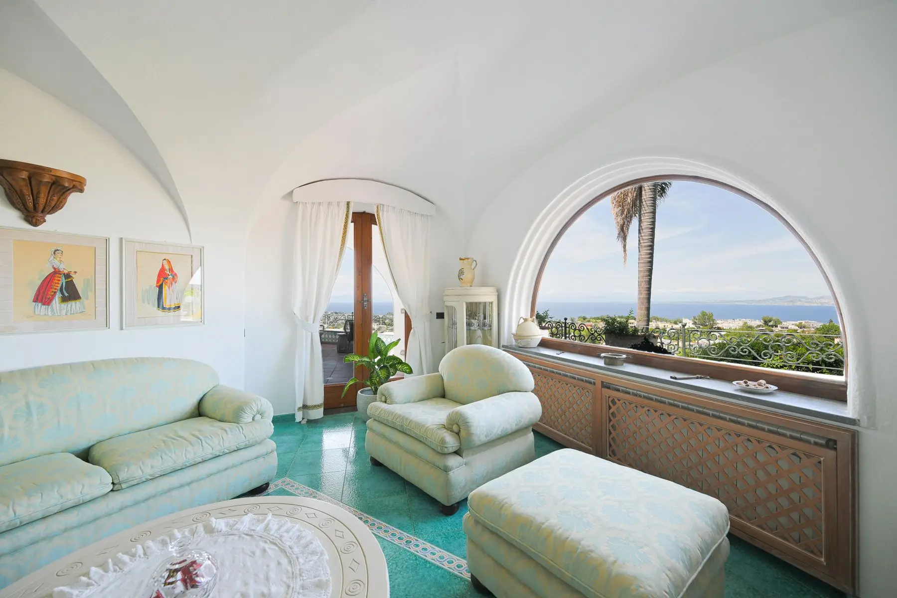 The lounge with pale sofas and the arched window onto the bay