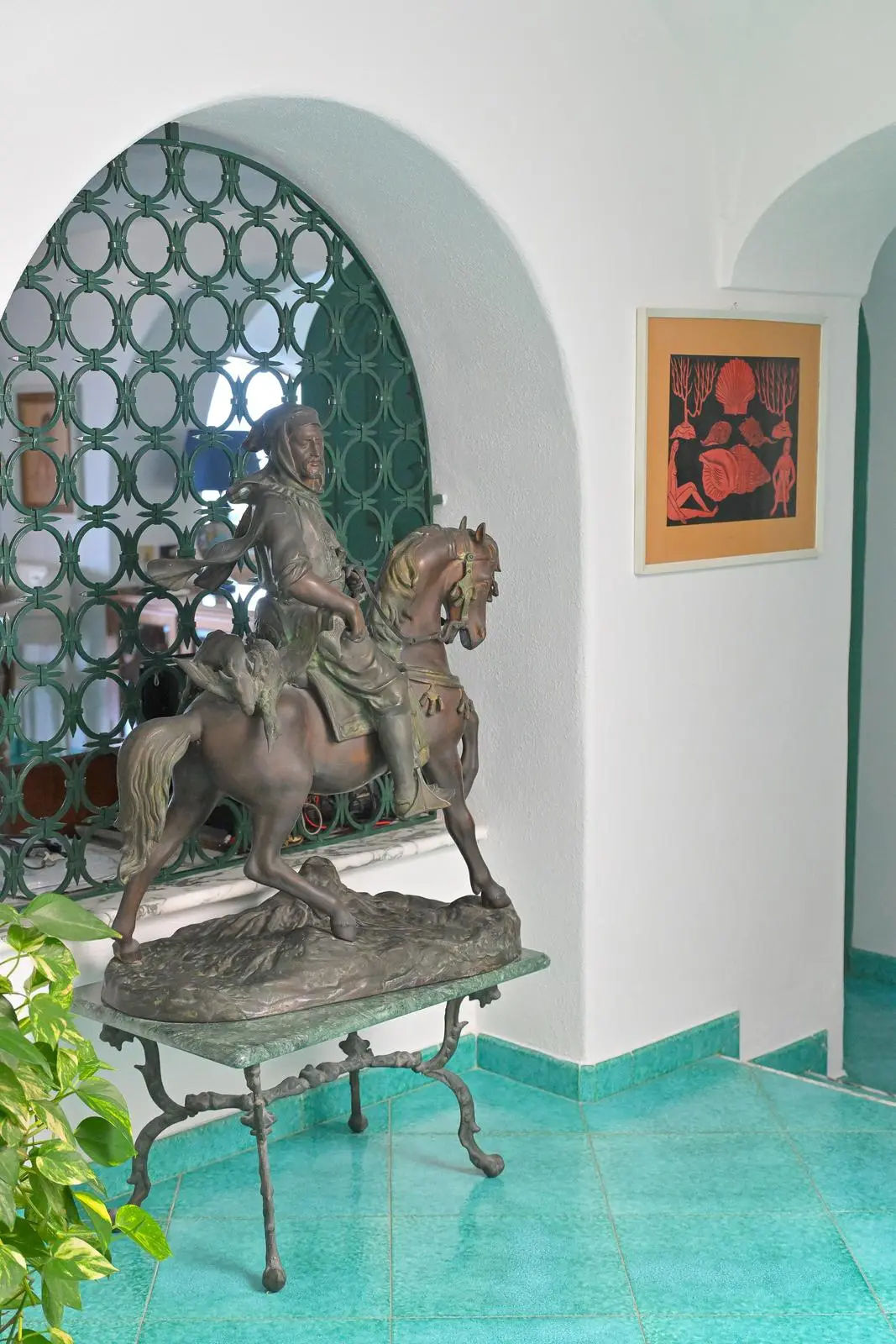 The bronze equestrian sculpture before the green arched grille