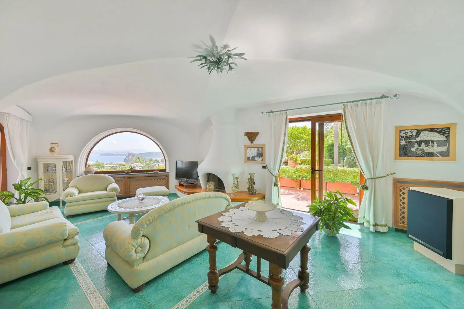 The lounge with white vaults, sofas and the arched window onto the sea