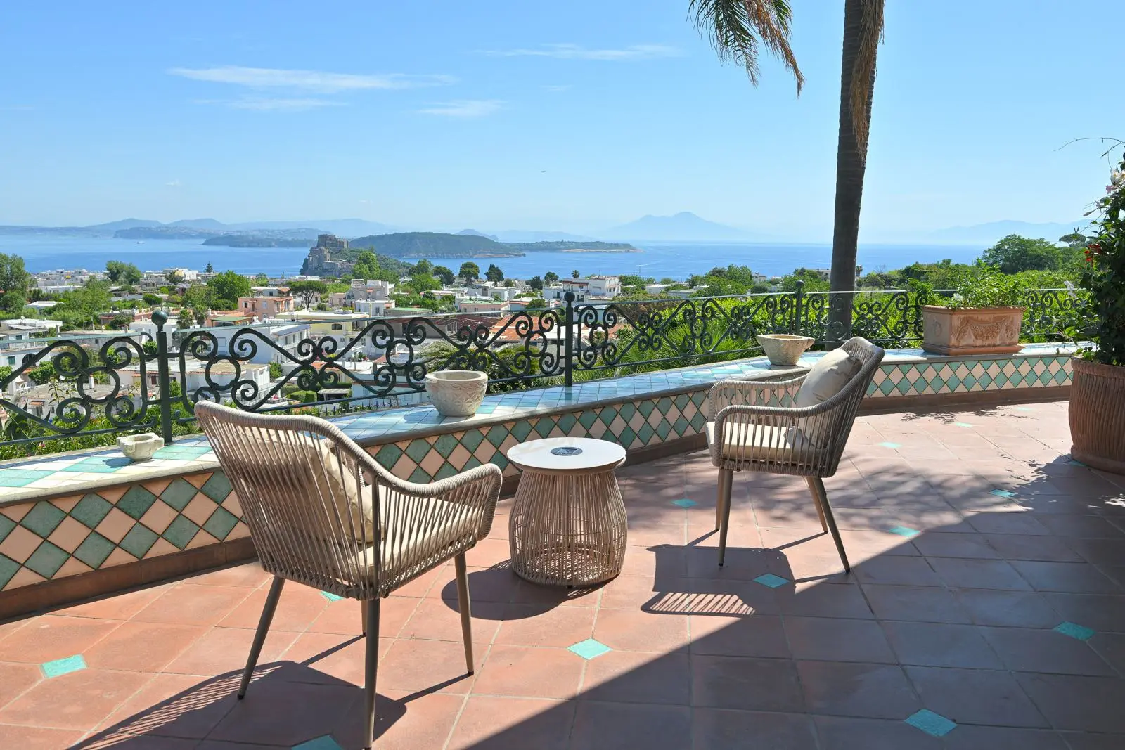 The majolica terrace with wicker armchairs facing the bay
